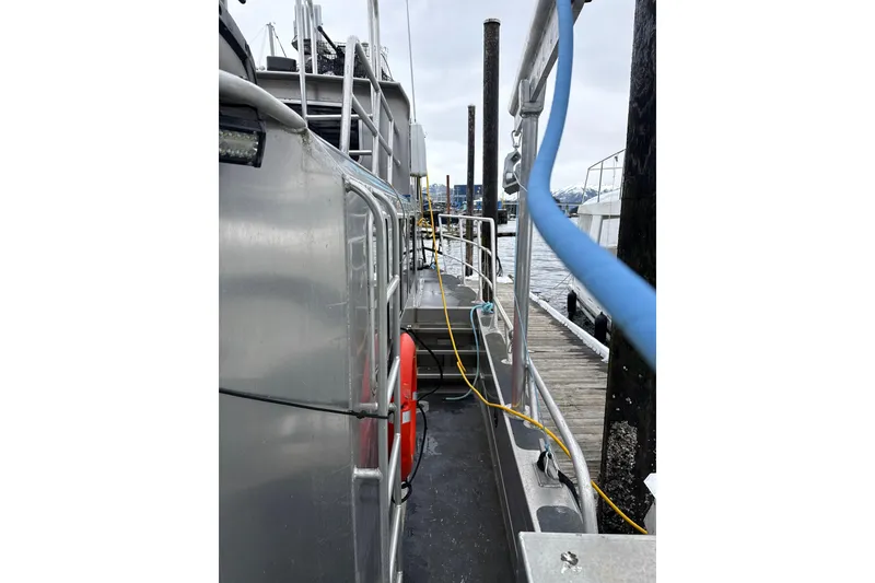 Slide: The Image of 2007 Armstrong Marine 36 Catamaran docked, showing side view with safety railings and cables. - 23