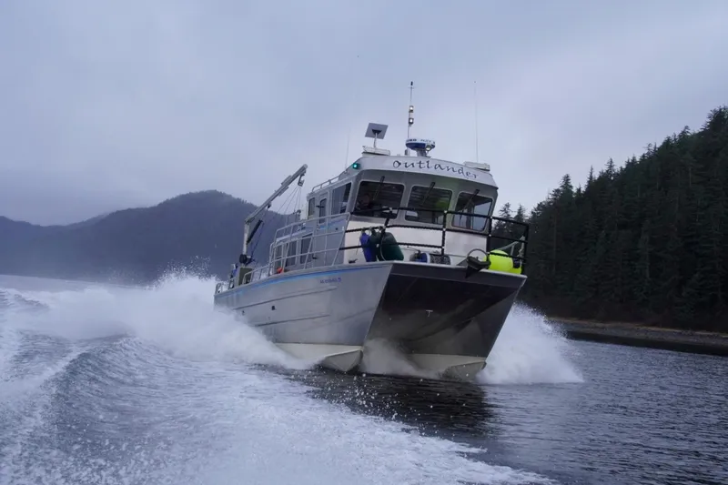 Slide: The Image of 2007 Armstrong Marine 36 Catamaran cruising through water with forested hills in background. - 36