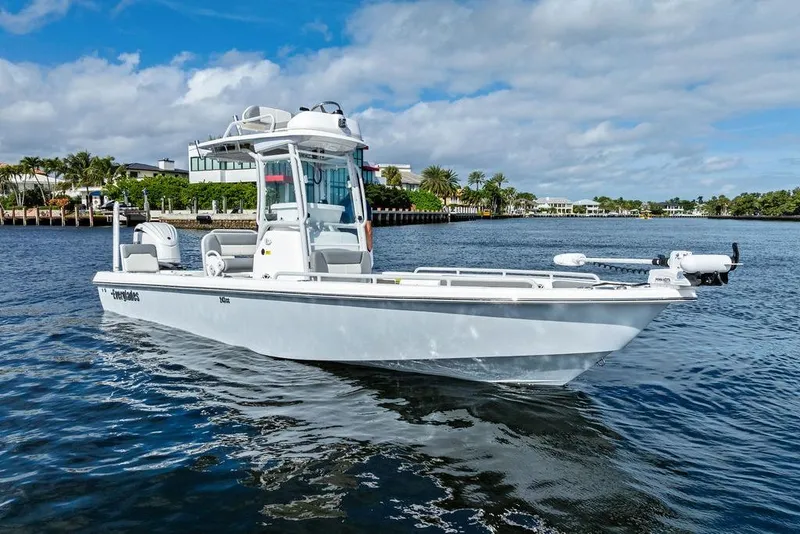 Slide: The Image of 2023 Everglades 243 Center Console boat on calm water, with scenic waterfront background. - 2