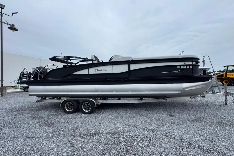 Slide: The Image of 2023 Barletta CORSA 25UC pontoon boat on trailer, parked on gravel lot. - 8