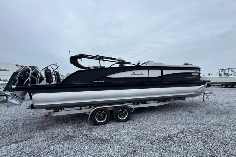 Slide: The Image of 2023 Barletta CORSA 25UC pontoon boat on a trailer, parked on gravel. - 9
