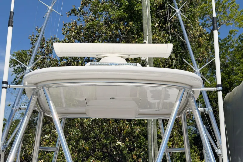 Slide: The Image of 1977 Bertram 31 Flybridge Cruiser with radar, viewed from below against a leafy backdrop. - 13