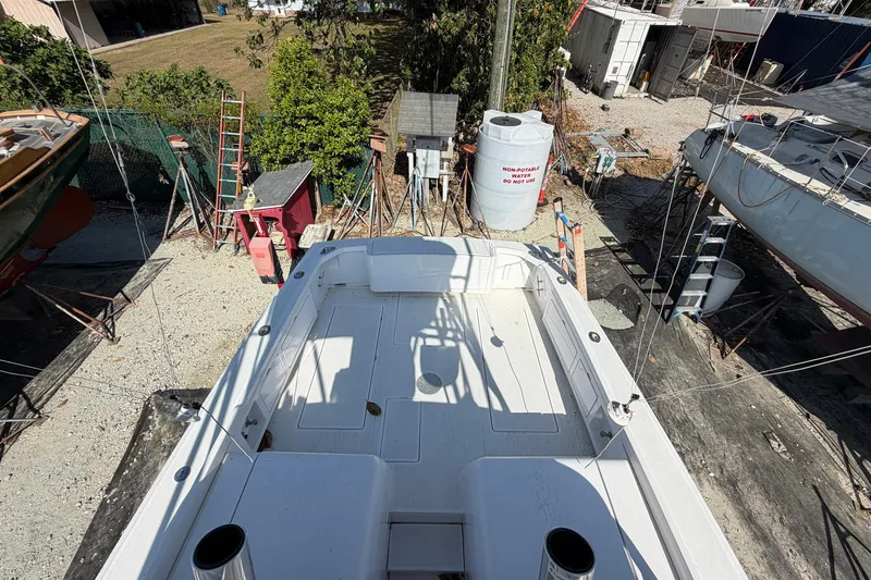 Slide: The Image of 1977 Bertram 31 Flybridge Cruiser on dry dock, surrounded by equipment and greenery. - 14