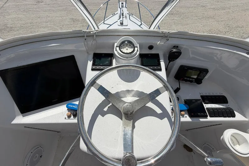 Slide: The Image of Cockpit view of a 1977 Bertram 31 Flybridge Cruiser with steering wheel and navigation instruments. - 16