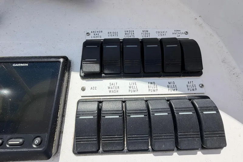 Slide: The Image of Control panel of a 1977 Bertram 31 Flybridge Cruiser with labeled switches and Garmin device. - 21