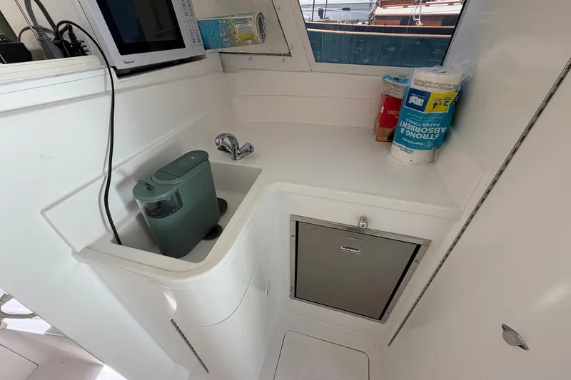 Slide: The Image of 1977 Bertram 31 Flybridge Cruiser galley with sink, microwave, and storage. - 25