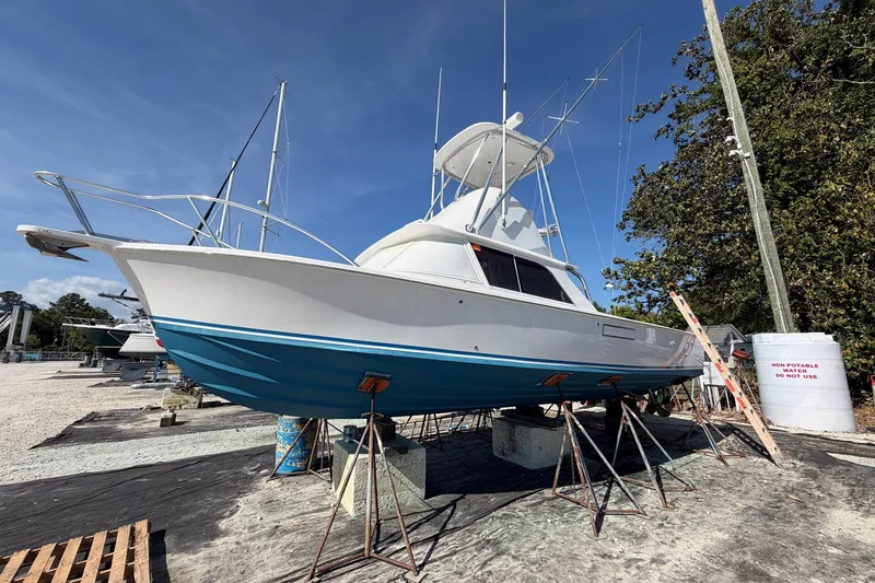 Slide: The Image of 1977 Bertram 31 Flybridge Cruiser on stands, ready for maintenance under clear skies. - 3