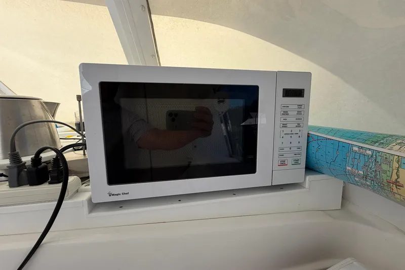 Slide: The Image of Microwave on 1977 Bertram 31 Flybridge Cruiser with nautical chart and kettle nearby. - 31