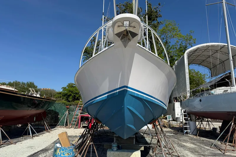Slide: The Image of 1977 Bertram 31 Flybridge Cruiser on dry dock, surrounded by other boats, under clear blue sky. - 5
