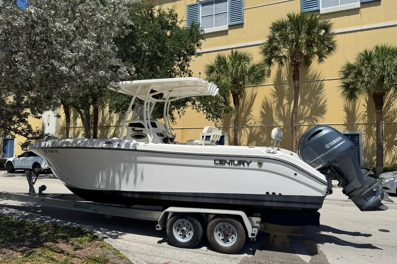 Slide: The Image of 2022 Century 2600 Center Console boat on trailer, parked near palm trees. - 2