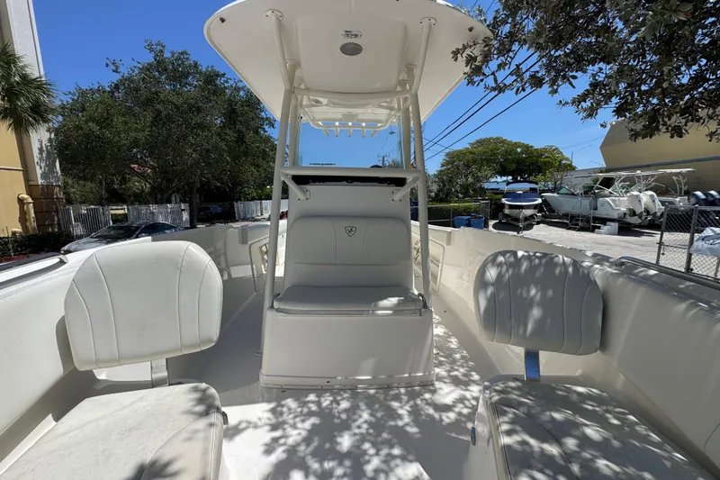 Slide: The Image of 2022 Century 2600 Center Console boat with white seating and canopy, parked outdoors. - 6