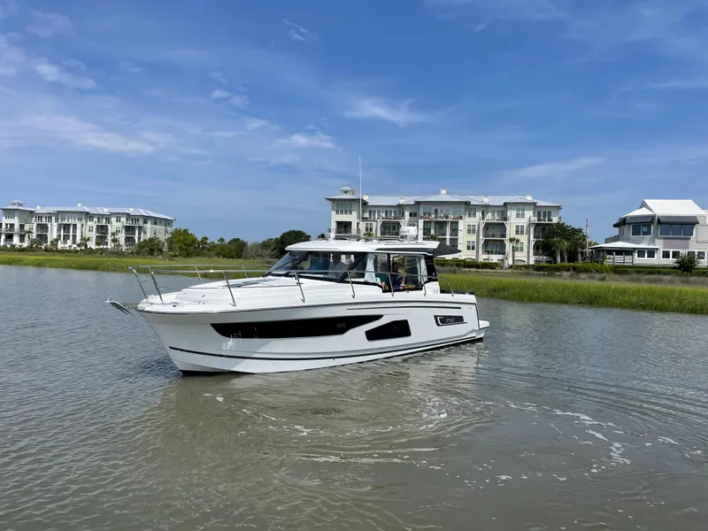 The Image of 2024 Jeanneau NC 1095 boat cruising near waterfront homes. - 0