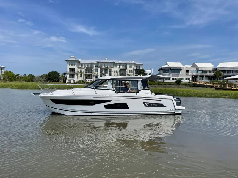 Slide: The Image of 2024 Jeanneau NC 1095 boat cruising near waterfront homes. - 1
