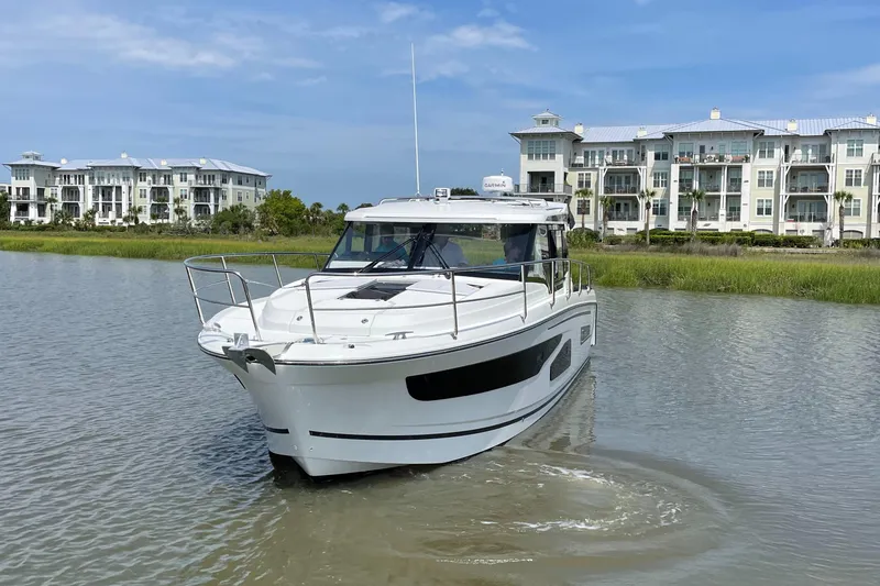 Slide: The Image of 2024 Jeanneau NC 1095 boat cruising near waterfront buildings. - 3
