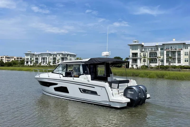 Slide: The Image of 2024 Jeanneau NC 1095 boat cruising near waterfront buildings. - 4