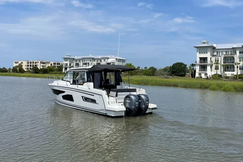Slide: The Image of 2024 Jeanneau NC 1095 boat cruising near waterfront homes. - 5