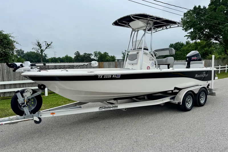 The Image of 2021 NauticStar 227 XTS boat on trailer, parked on a suburban street. - 1