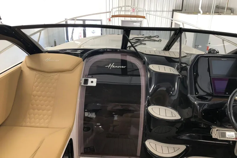Slide: The Image of 2024 Hanover 305 boat interior with tan seating and sleek black dashboard. - 13
