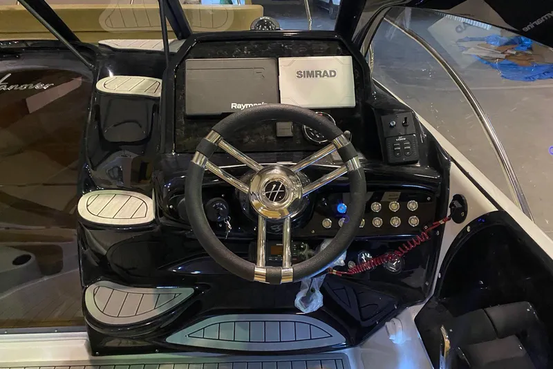 Slide: The Image of 2024 Hanover 305 boat dashboard with steering wheel, Raymarine and Simrad navigation systems. - 14