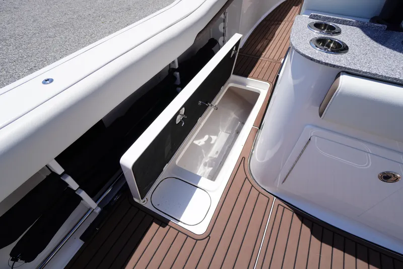 Slide: The Image of 2024 Tidewater 320 CC Adventure boat interior with open storage compartment and cup holders. - 24
