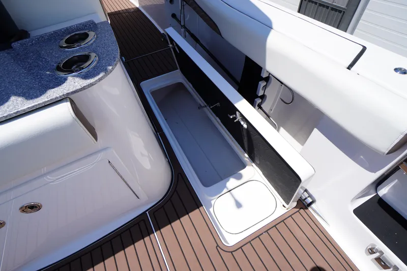 Slide: The Image of 2024 Tidewater 320 CC Adventure boat interior with open storage compartment and cup holders. - 25