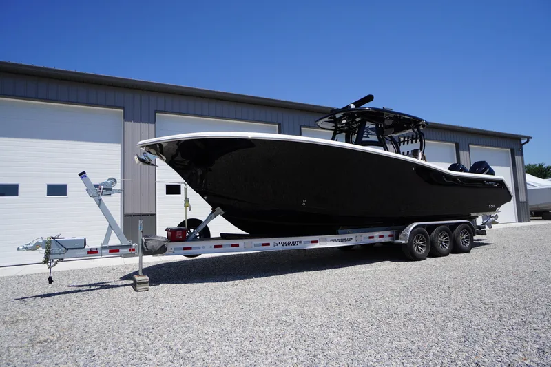 Slide: The Image of 2024 Tidewater 320 CC Adventure boat on trailer, parked outside a garage. - 3