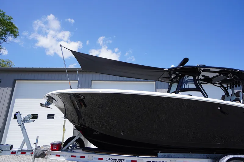 Slide: The Image of 2024 Tidewater 320 CC Adventure boat on trailer, under clear blue sky. - 4