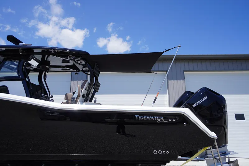 Slide: The Image of 2024 Tidewater 320 CC Adventure boat with Mercury engines, docked under a clear blue sky. - 5