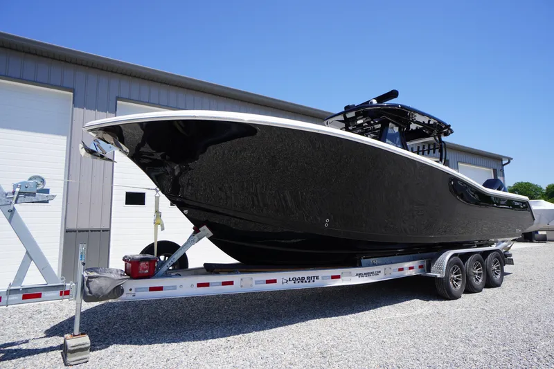 Slide: The Image of 2024 Tidewater 320 CC Adventure boat on trailer, sleek black design, parked outdoors. - 6