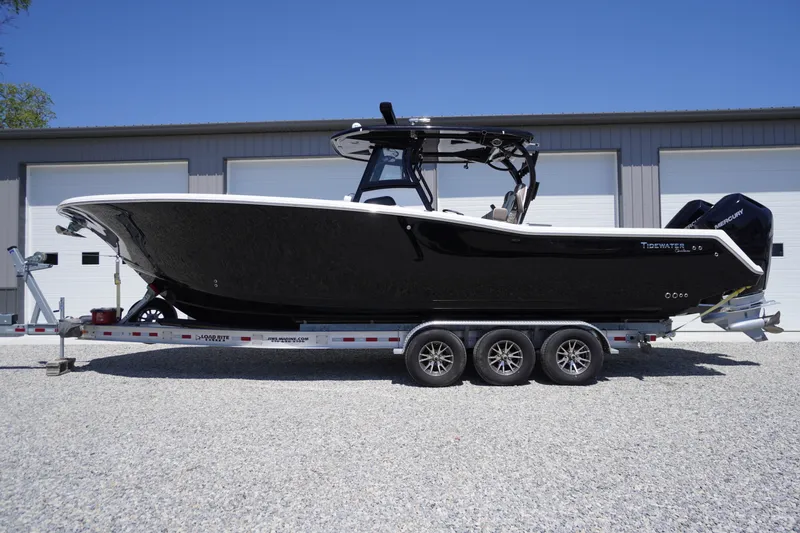 Slide: The Image of 2024 Tidewater 320 CC Adventure boat on trailer, black hull, parked outdoors. - 8