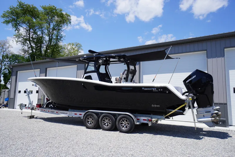 Slide: The Image of 2024 Tidewater 320 CC Adventure boat on trailer, parked outdoors under blue sky. - 9