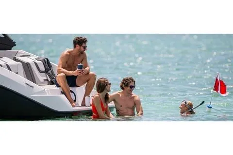 Slide: The Image of People enjoying water activities near a 2025 Yamaha AR220 boat. - 6