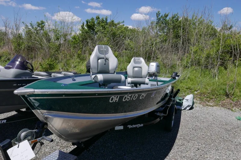 Slide: The Image of 2002 Lund 1440-V Rebel Tiller boat on trailer, parked outdoors. - 2