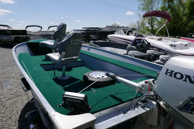 Slide: The Image of 2002 Lund 1440-V Rebel Tiller boat with Honda motor, green interior, and fishing seats. - 3