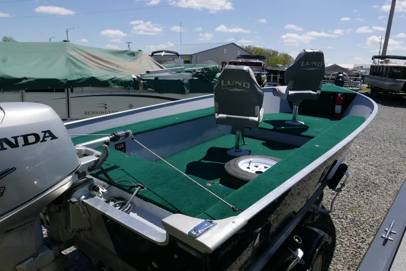 Slide: The Image of 2002 Lund 1440-V Rebel Tiller boat with Honda motor, green interior, and dual seats. - 4
