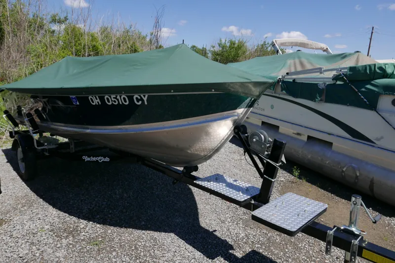 Slide: The Image of 2002 Lund 1440-V Rebel Tiller boat on trailer with green cover. - 6