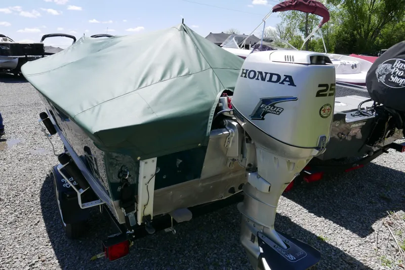 Slide: The Image of 2002 Lund 1440-V Rebel Tiller boat with Honda 25HP outboard motor, covered and parked outdoors. - 7