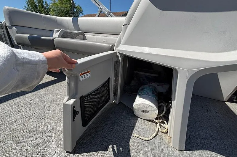 Slide: The Image of 2022 Godfrey Sweetwater 2286 SBX boat storage compartment with open door, revealing interior items. - 11