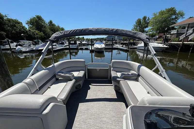 Slide: The Image of 2022 Godfrey Sweetwater 2286 SBX pontoon boat docked, featuring spacious seating and canopy. - 13