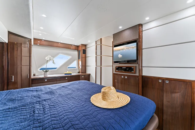 Slide: The Image of Luxurious 2007 Marquis 55 LS yacht bedroom with blue bedding, TV, and elegant wood finishes. - 58