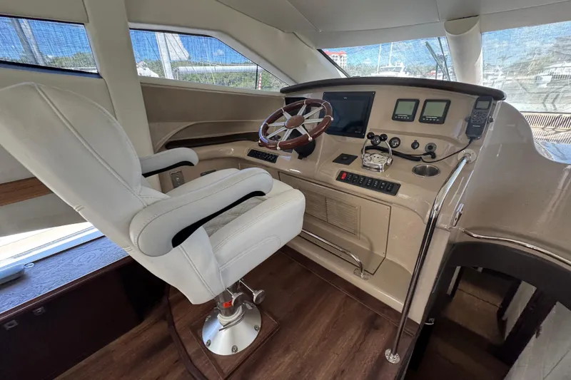 Slide: The Image of 2007 Marquis 55 LS yacht docked in a marina, surrounded by calm waters and scenic buildings. - 6