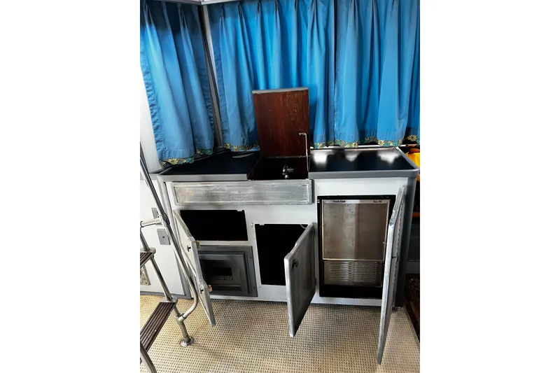 Slide: The Image of 1988 Chris Craft Constellation yacht kitchen with blue curtains and stainless steel appliances. - 10