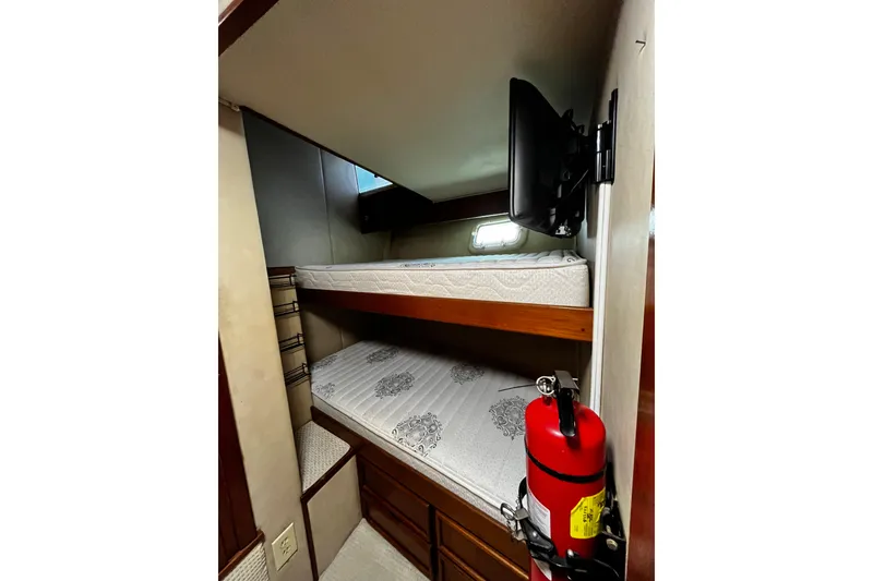 Slide: The Image of 1988 Chris Craft Constellation cabin with bunk beds and a mounted TV. - 22