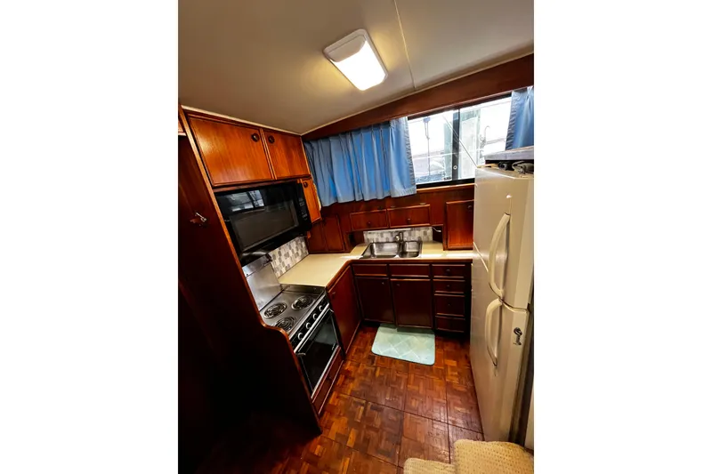 Slide: The Image of 1988 Chris Craft Constellation kitchen with wood cabinetry, stove, microwave, and refrigerator. - 19