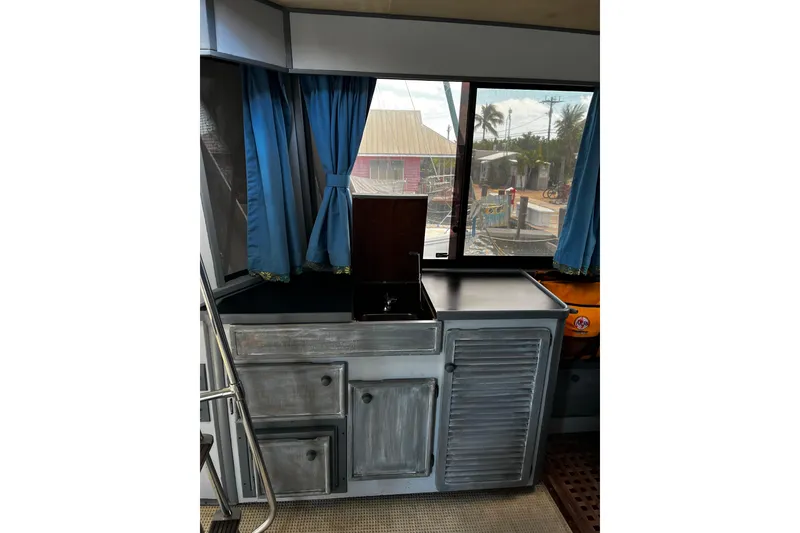 Slide: The Image of 1988 Chris Craft Constellation interior with blue curtains and compact kitchenette. - 9
