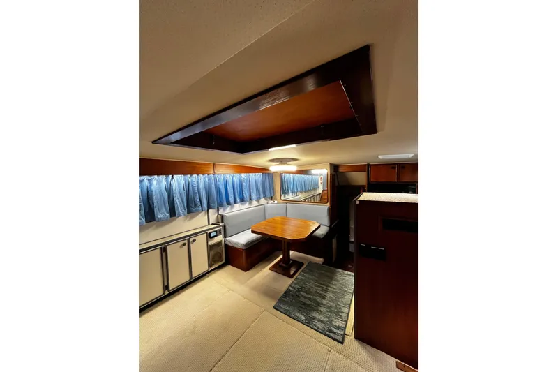 Slide: The Image of 1988 Chris Craft Constellation yacht interior with dining area, blue curtains, and wooden accents. - 15