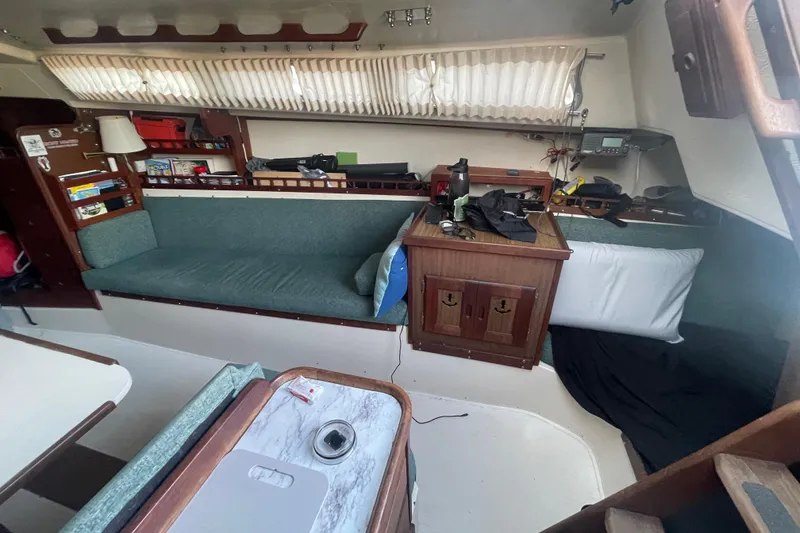 Slide: The Image of Interior of a 1977 Catalina sailboat with cozy seating and wooden cabinetry. - 10