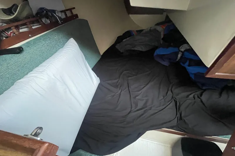 Slide: The Image of Cozy sleeping area inside a 1977 Catalina boat with bedding and storage. - 12
