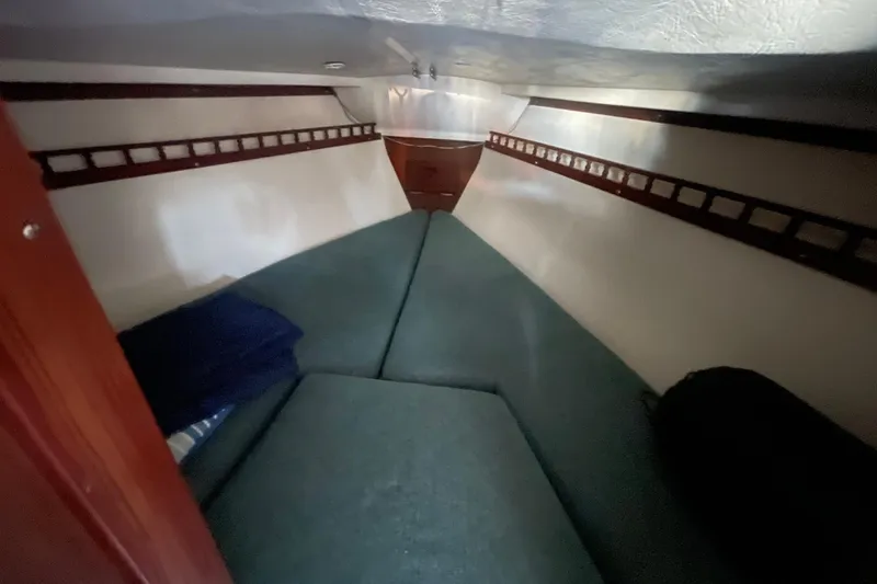 Slide: The Image of Interior cabin of a 1977 Catalina boat with green cushions and wooden accents. - 13
