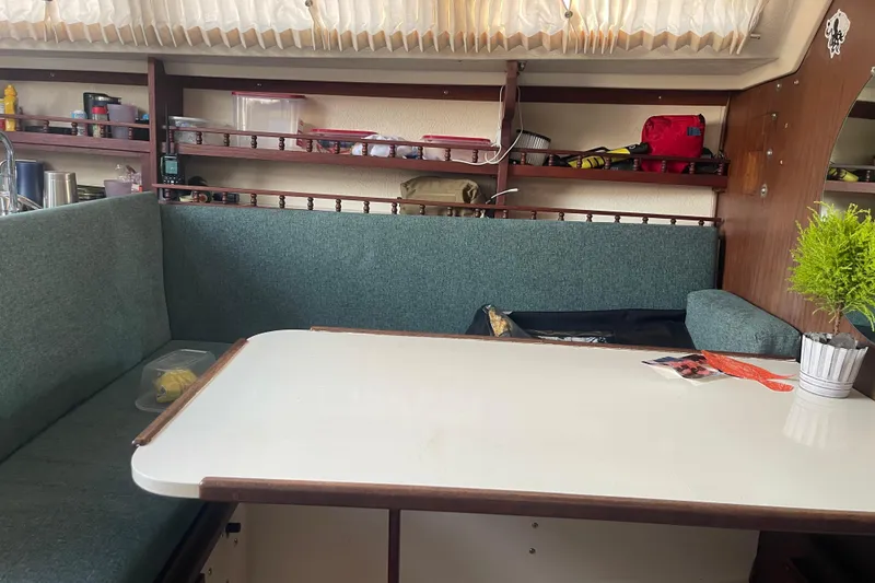 Slide: The Image of Cozy 1977 Catalina boat interior with teal seating, white table, and organized shelves. - 15